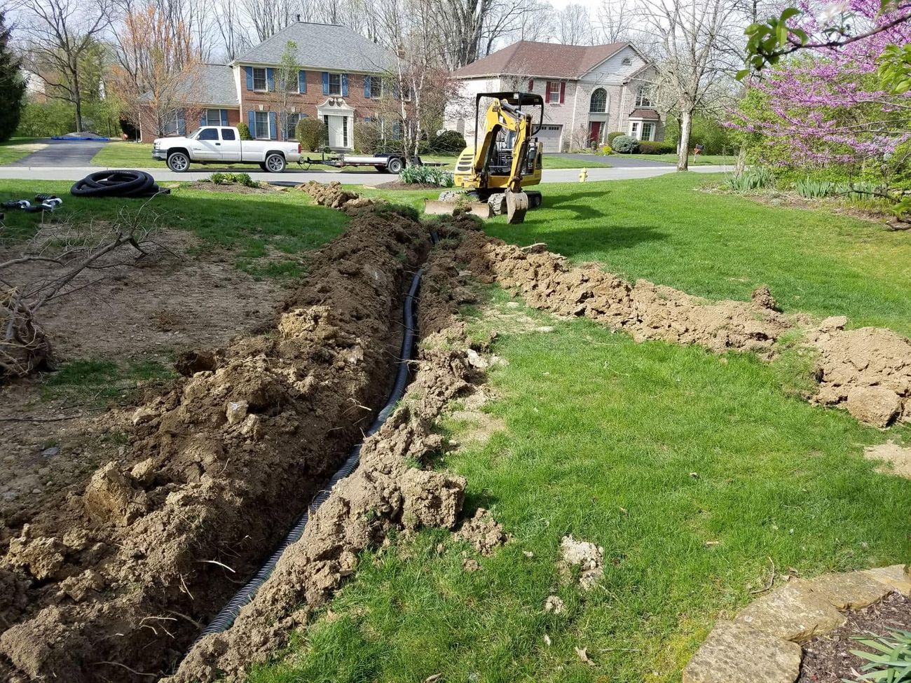 A trench cut across a lawn with a mini excavator